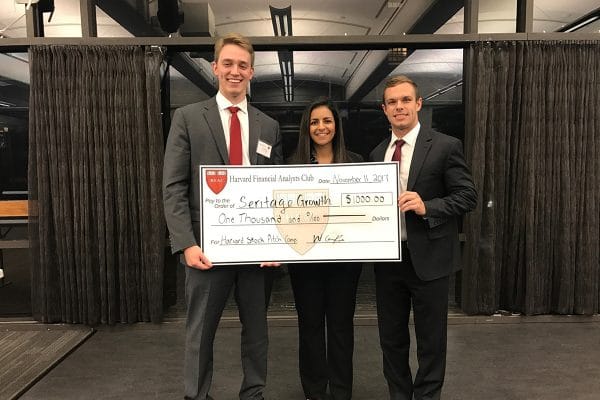Three finance students hold a large check from their win at a Harvard Case Competition