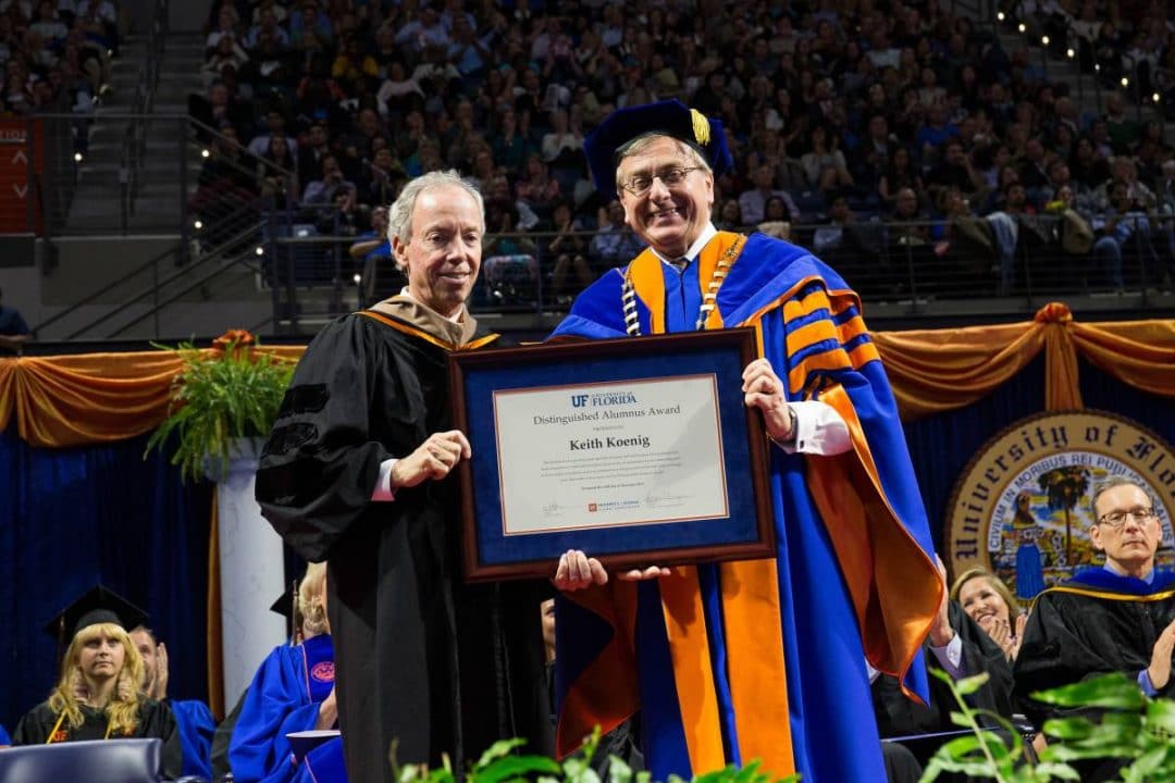 UF President Kent Fuchs hands Keith Koenig a framed distinguished alumnus award at commencement