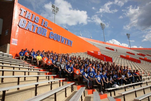 Large group of students sit in the UF Football stadium under a sign that reads This is Gator Country