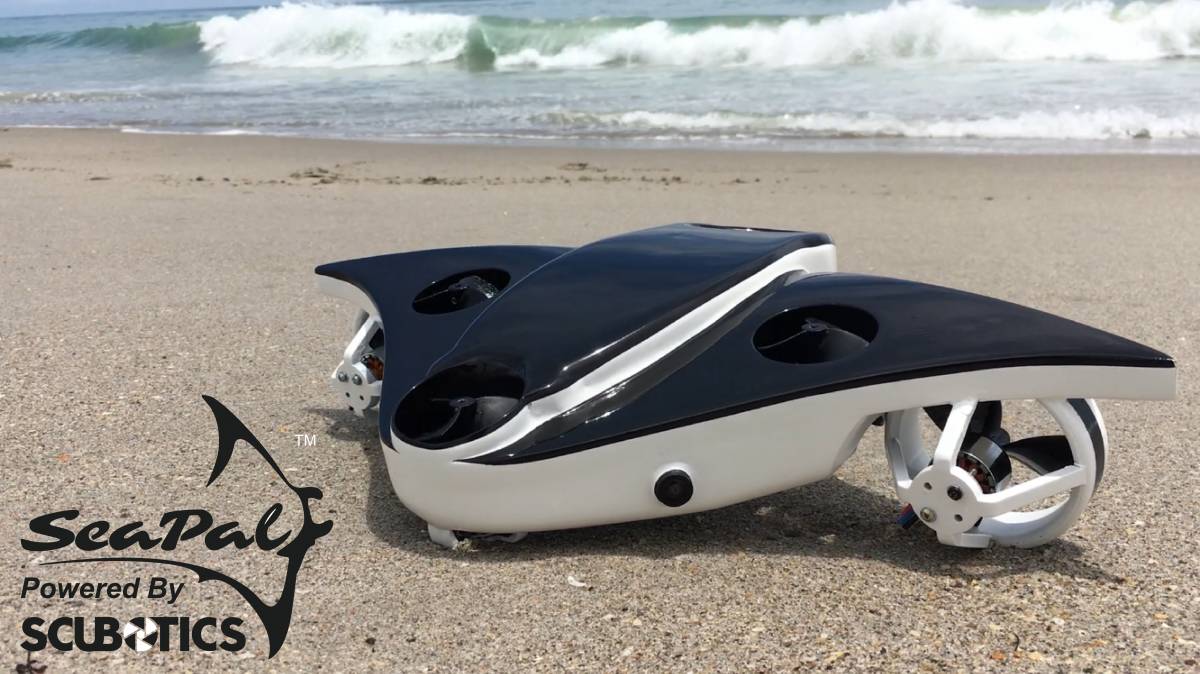 SeaPal, powered by SCUBOTICS, the underwater drone is pictured on a sandy beach with waves in the background