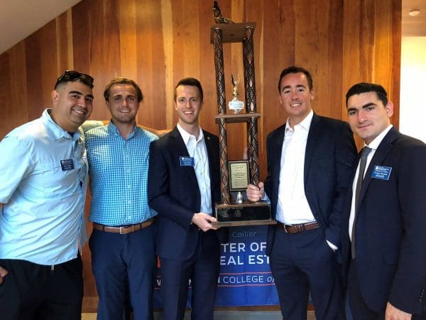 Five male real estate students hold a trophy