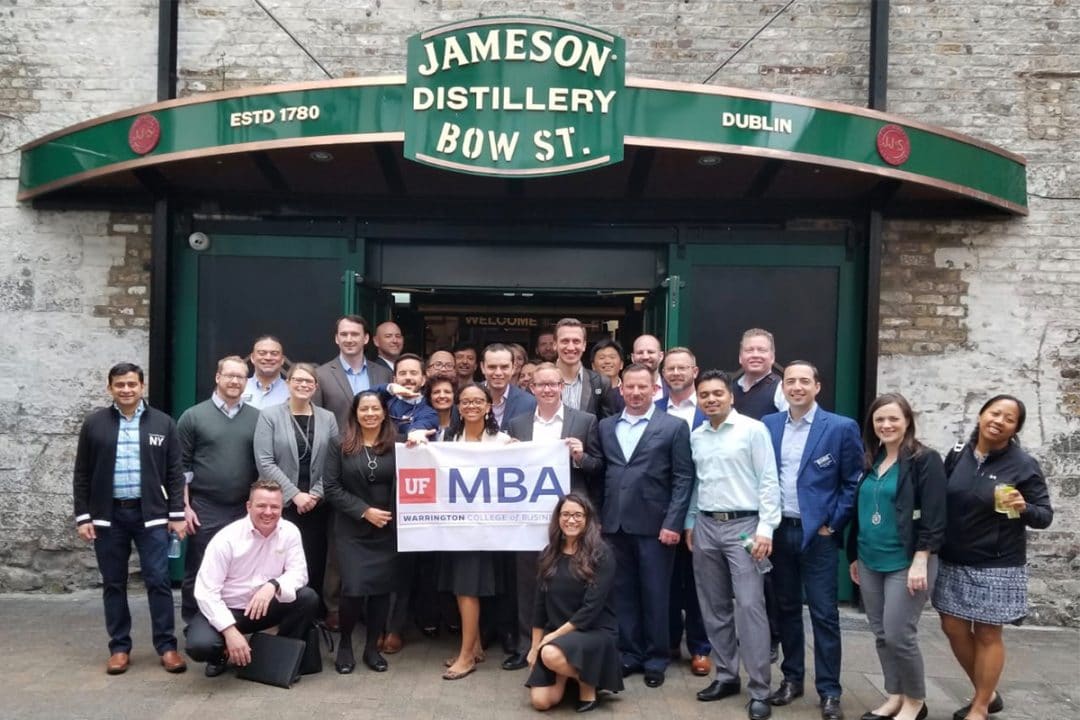 UF MBA students stand in front of the Jameson Distillery in Dublin holding a UF MBA banner