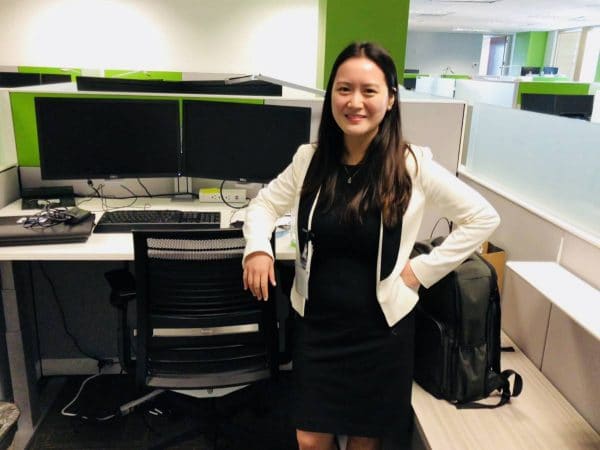 Victoria Liu stands at her desk at her internship