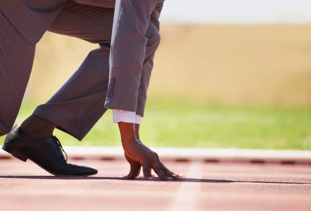View of a man in a track starting position wearing a business suit