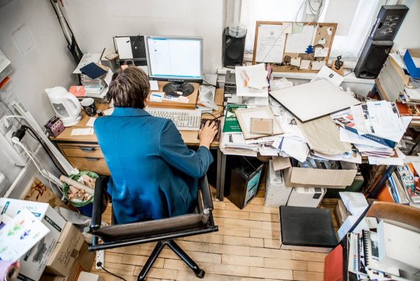 High Angle View Of Office Worker Working On Computer with a cluttered desk