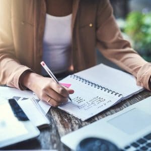 Woman writes a list in front of a computer