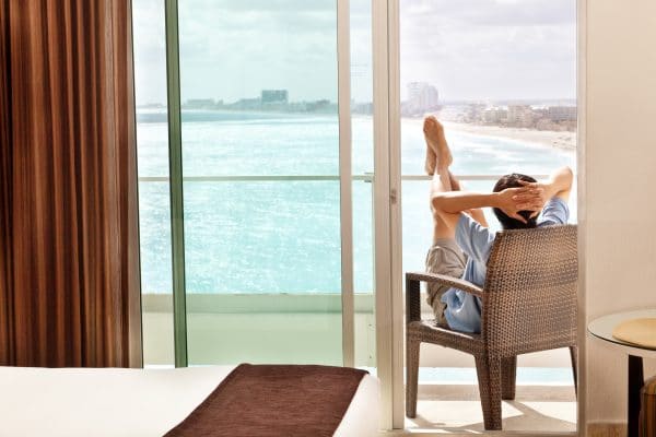 Man on vacation, sunbathing and enjoying the view of the Caribbean Sea from the room balcony of a resort hotel in Cancun, Riviera Maya, Mexico.