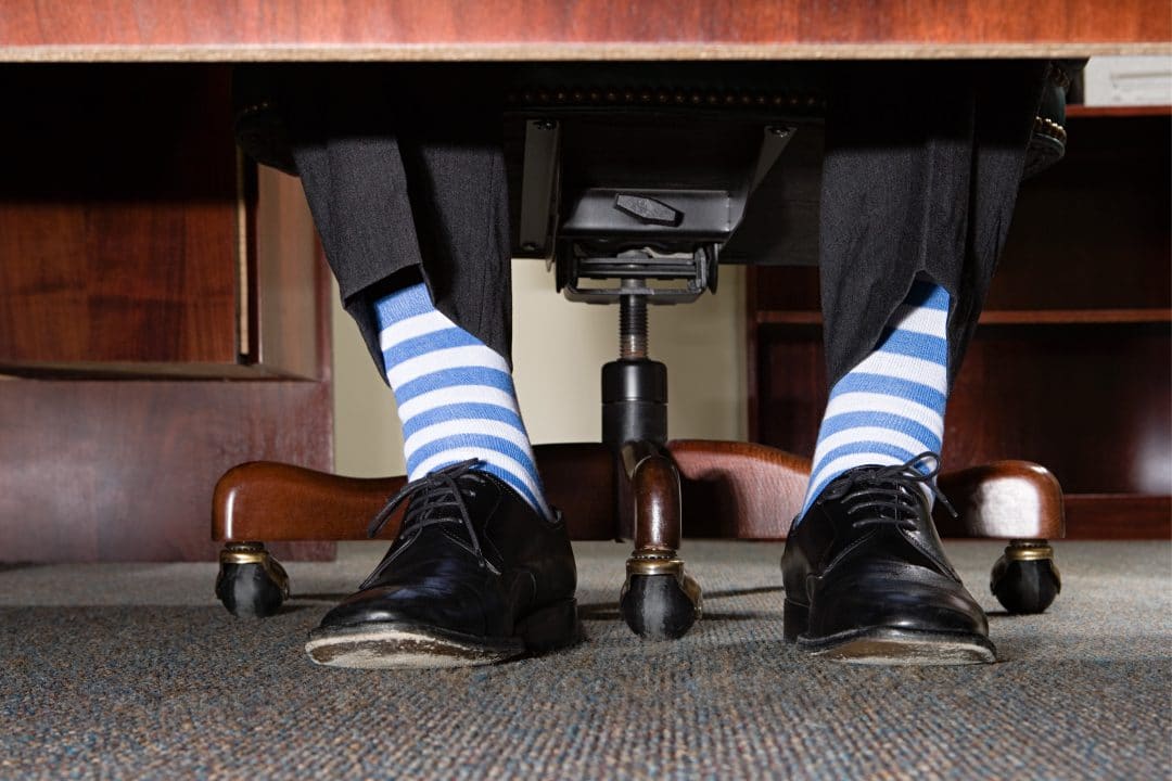 View of businessman with striped socks from under a desk.