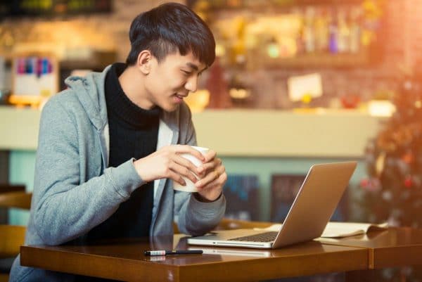 Young man looking at a computer drinking coffee