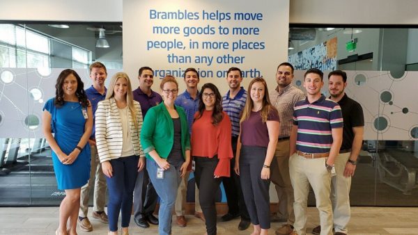 12 people stand in front of a Brambles logo