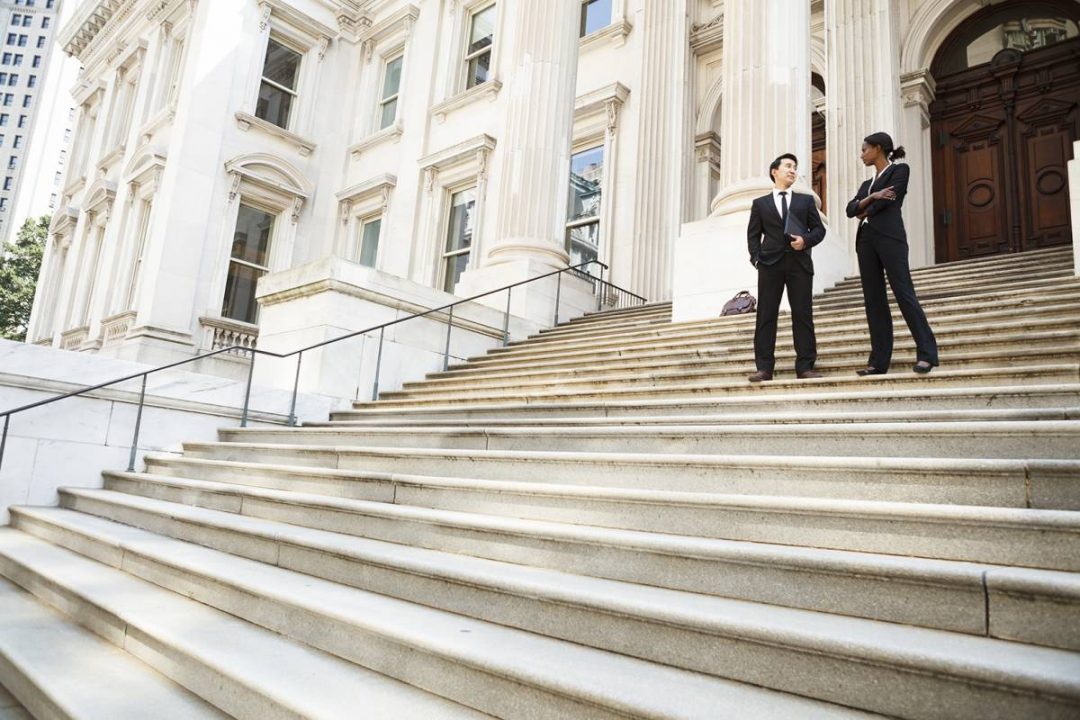 Male and female lawyer talking on courthouse steps