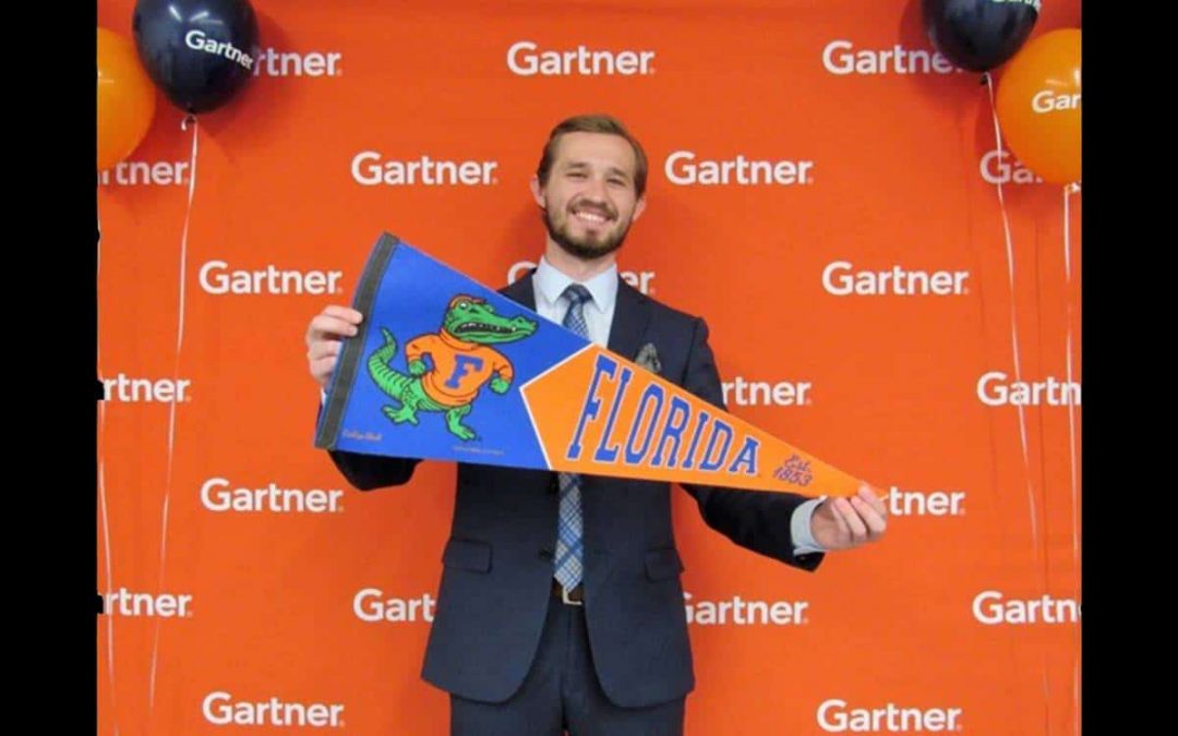 David Ousley holds a University of Florida pennant in front of a Gartner step and repeat