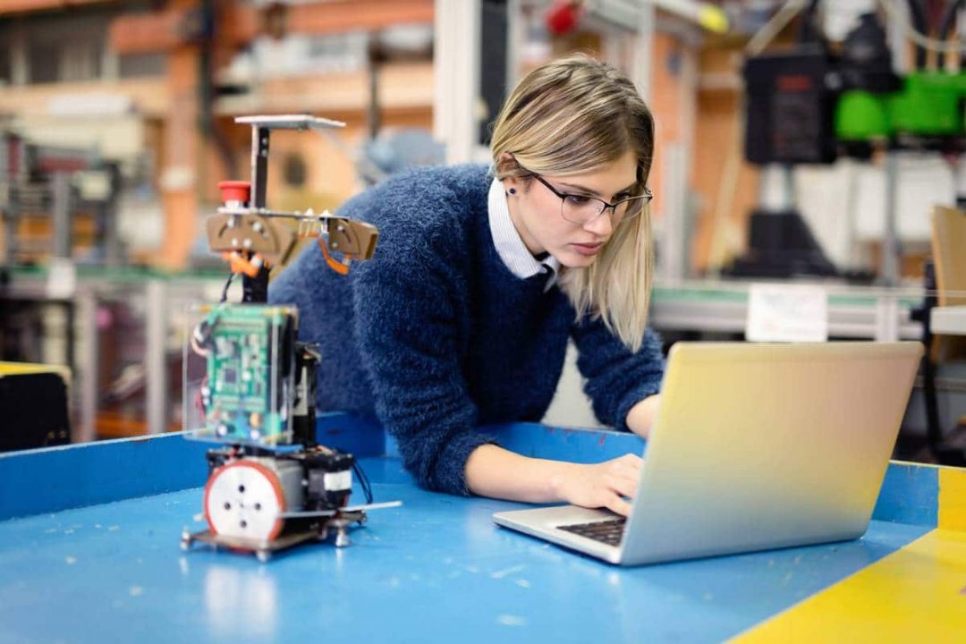Young woman engineer working on robotics project using laptop