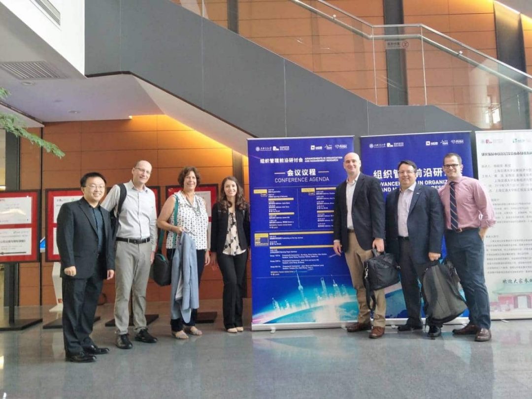 Seven faculty members from Warrington's management department pose in front of the conference sign in China