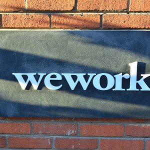 WeWork logo on a sign on a brick wall