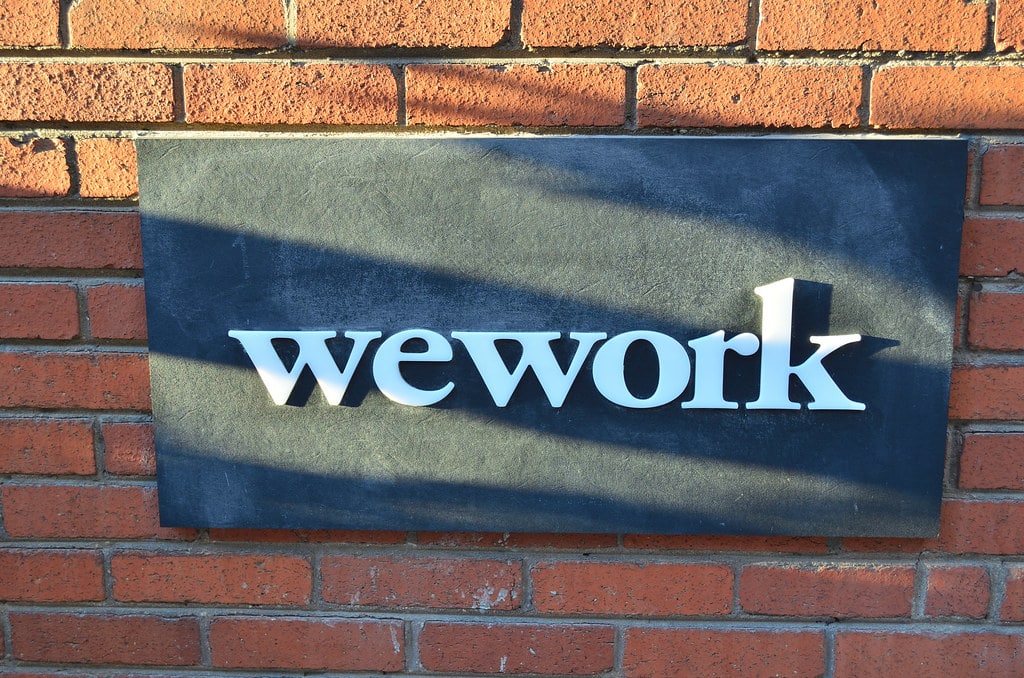 WeWork logo on a sign on a brick wall
