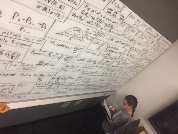 Student looking at a large white board filled with financial equations