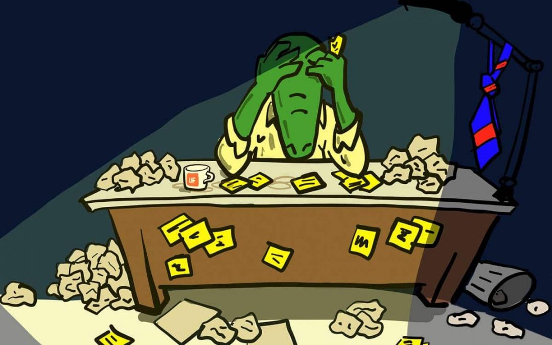 Cartoon gator sitting at a desk with lots of crumpled up papers looking down with his head in his hands