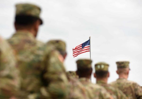 American Soldiers standing below US Flag