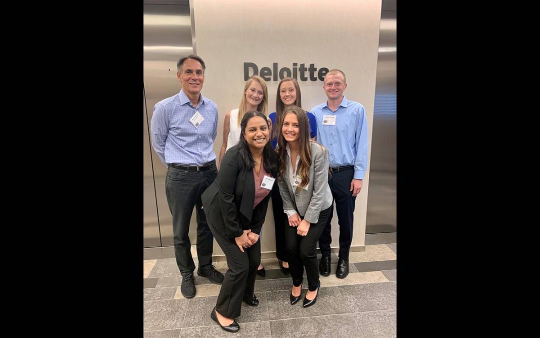 Five students and their faculty advisor pose for a photo at Deloitte