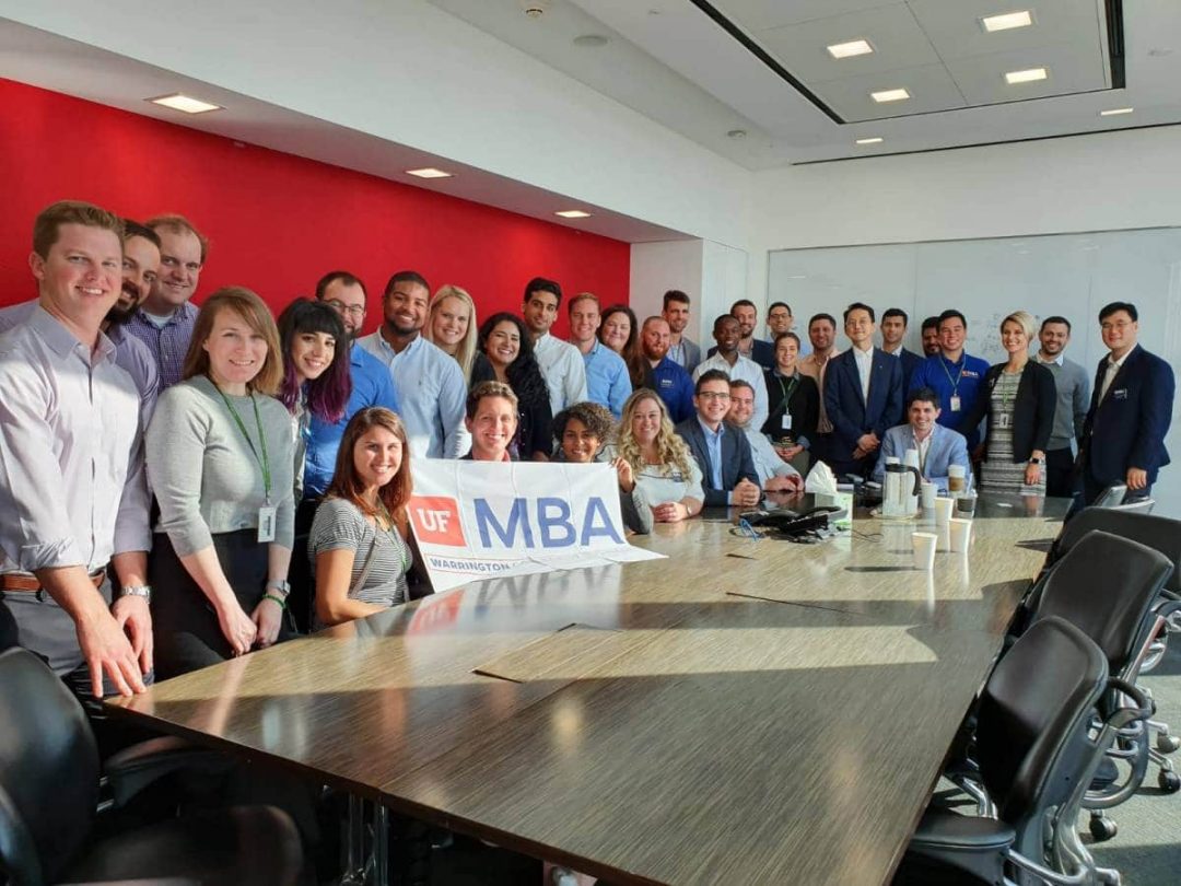UF MBA students at a large conference table with a UF MBA banner