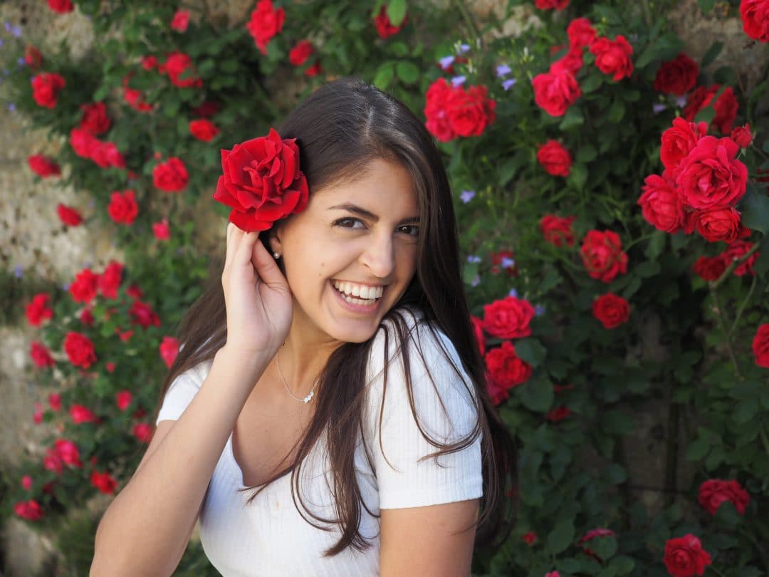 Abbigail Halem in front of a rose wall with a rose in her hair