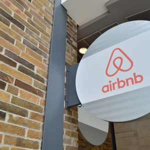Circular sign with airbnb triangle logo mounted on a brick wall outside