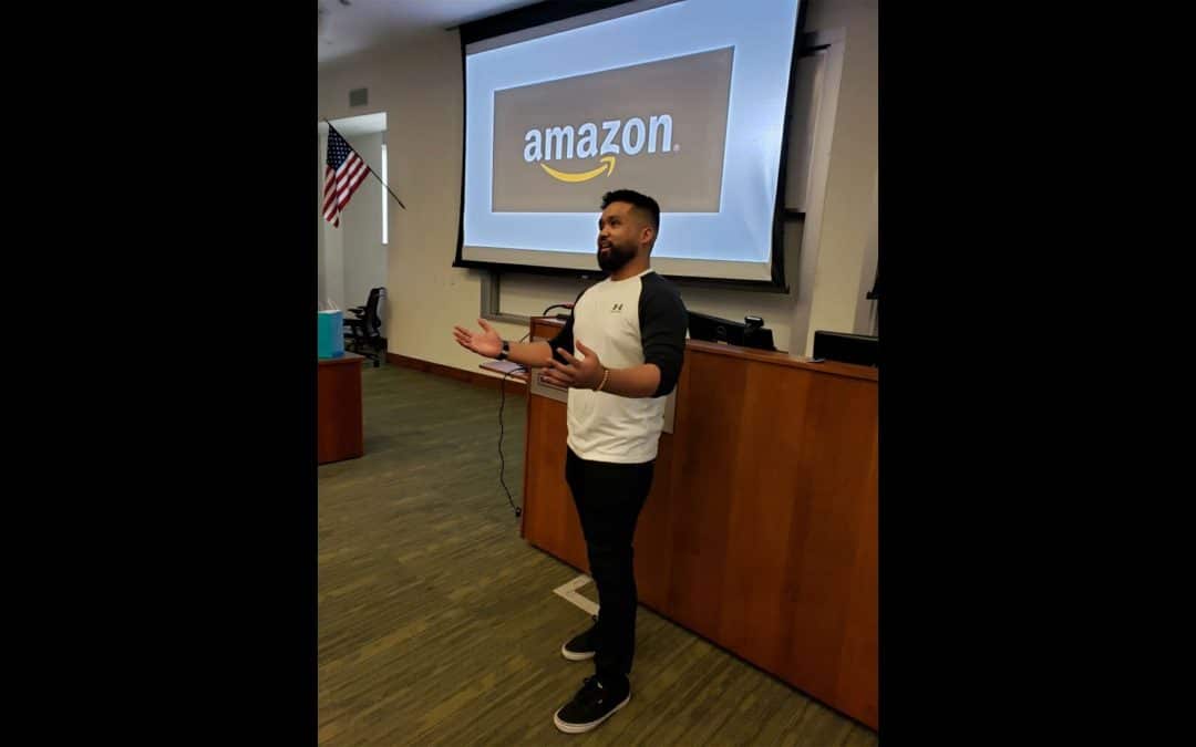Carlo Claudio speaks in a classroom with a projection of the Amazon logo behind him