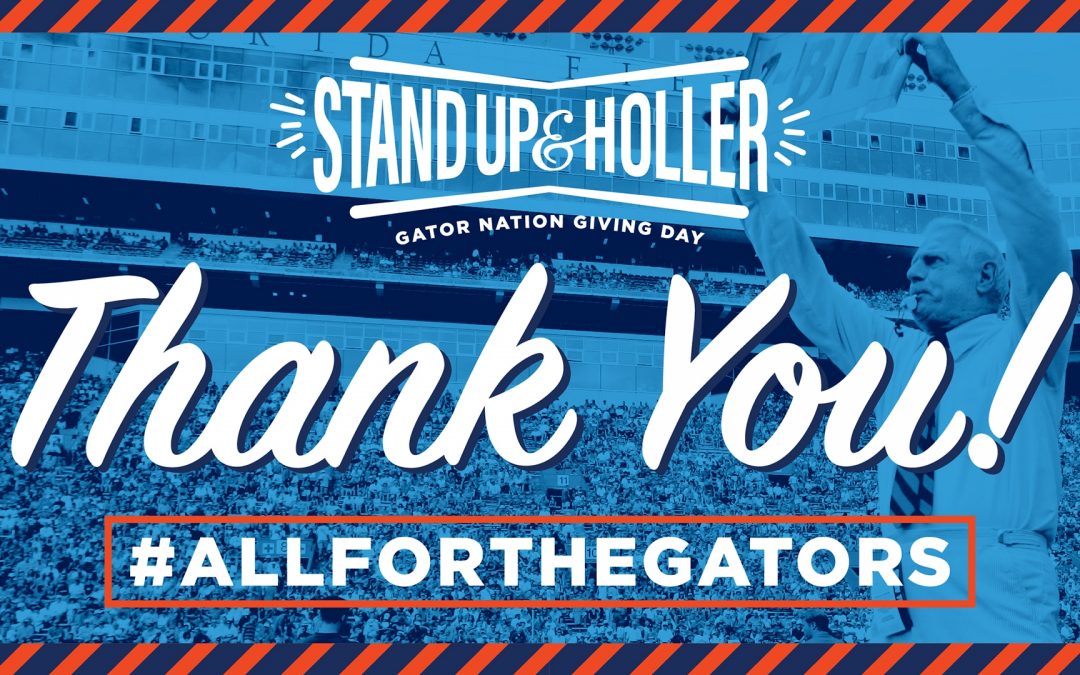 Mr. Two Bits holding a sign in Ben Hill Graiffin stadium with blue tint. Text over the image reads Sand Up and Holler Thank you! #AllfortheGators