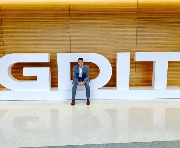NIck Tharp sits in a large logo for GDIT