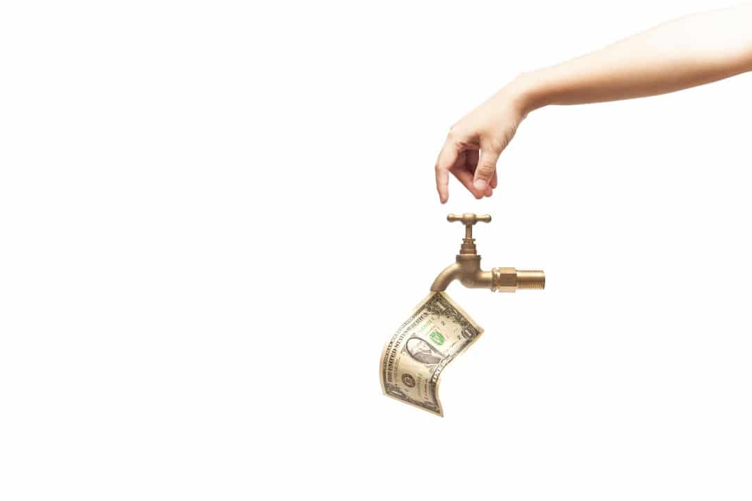 Hand opening the water tap, money falling from the water tap isolated on white background, financial concept.