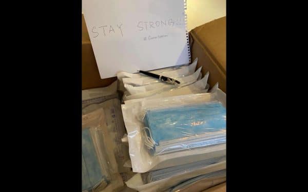 A shipping box full of face masks wrapped in plastic with a handwritten note that says Stay Strong #GatorNation