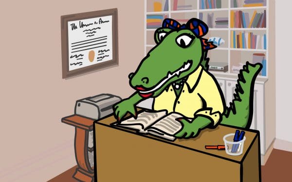 Cartoon Alberta Gator sitting at a desk reading a book. Her UF degree hangs on the wall to her right and a bookshelf filled with books is behind her.