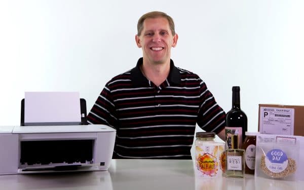 Dave Carmany sitting at a table with a printer and products with labels from his company, OnlineLabels.com.