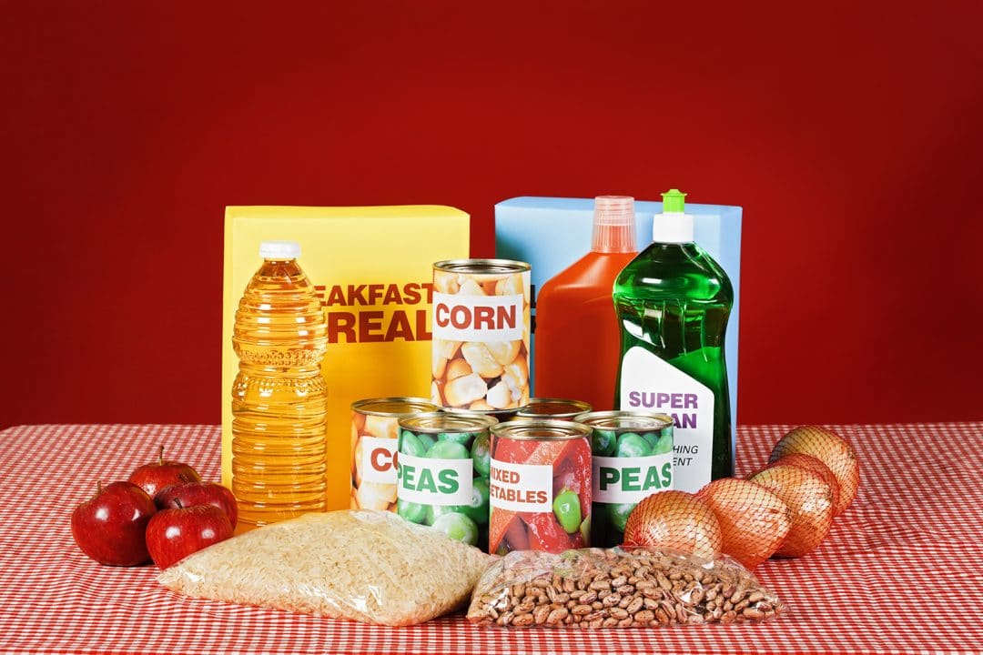 Generic food and cleaning products on gingham against red.