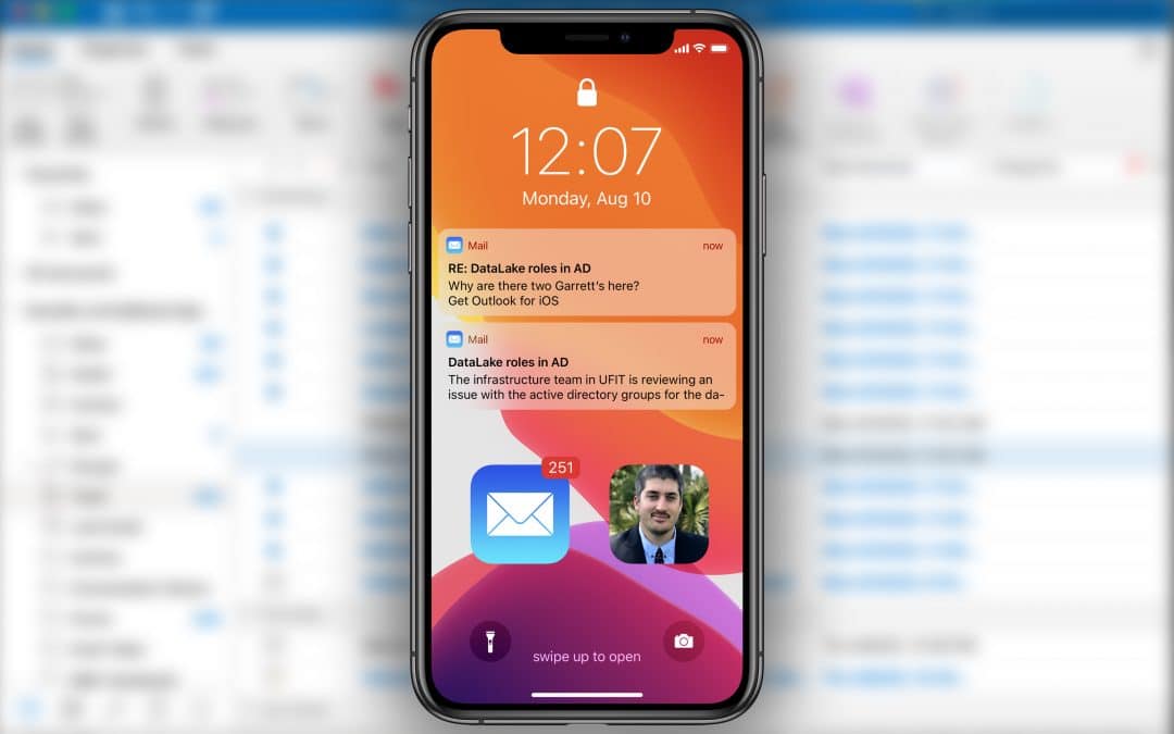 Blurred Microsoft Outlook email background with an iPhone in the foreground that has two Outlook email notifications and a photo of James Martinez