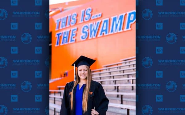 Monique Atkinson poses for a photo in a graduation cap and gown in the Swamp. Text behind her reads This is...The Swamp.