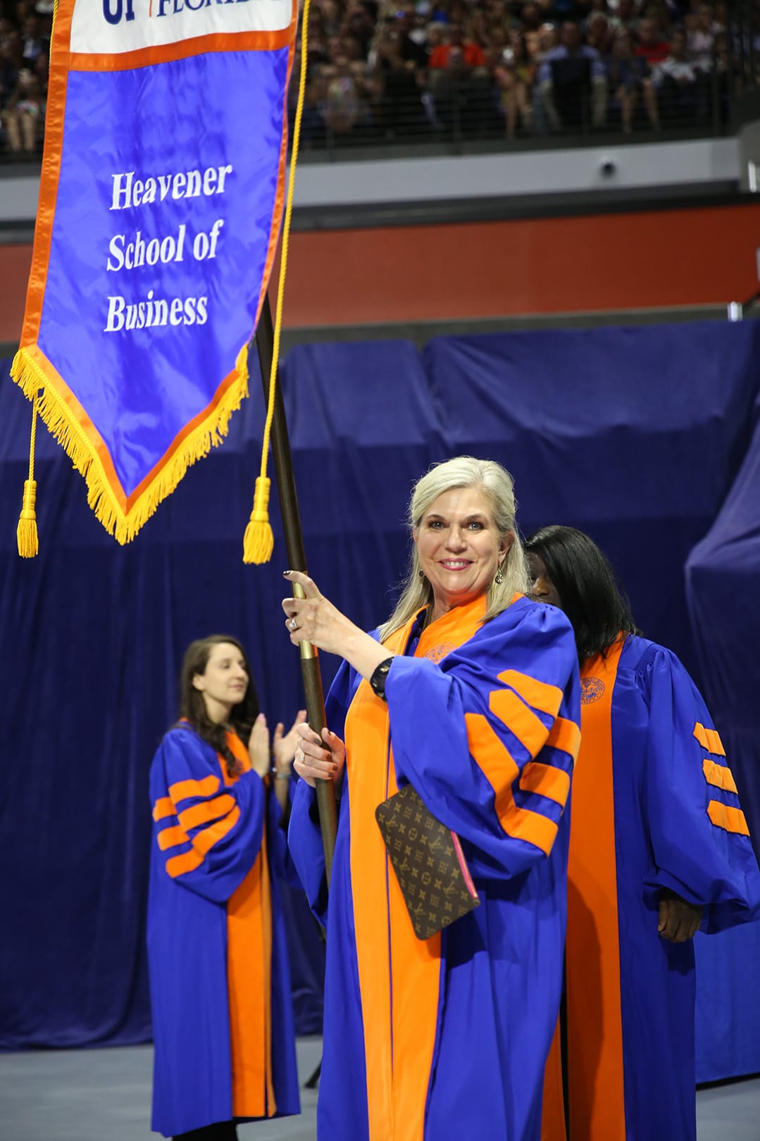 Betsy Goodman holds the Heavener School of Business flag at Commencement