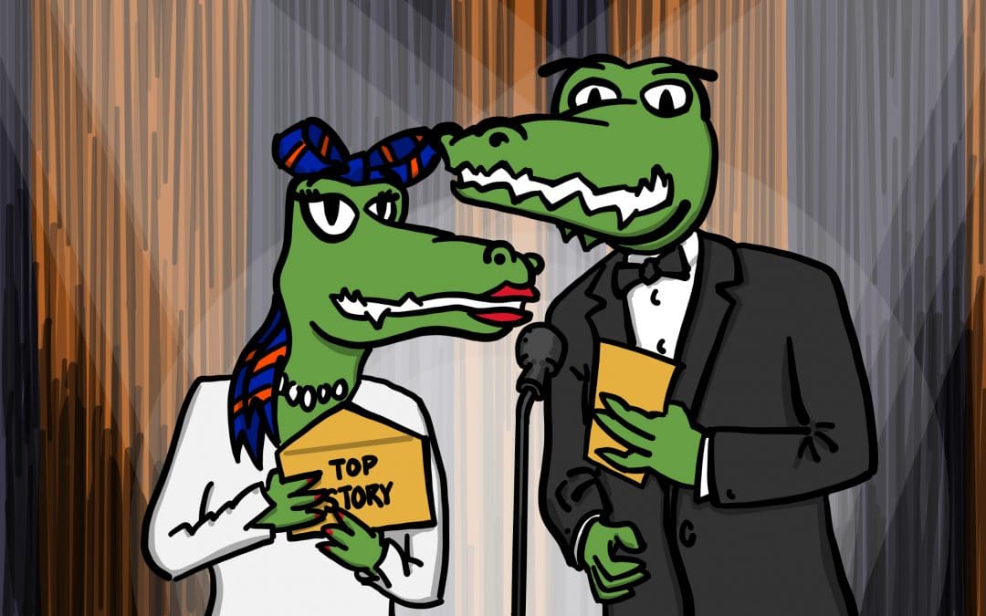 Alberta and Albert Gator stand in front of a microphone on a stage presenting the "top story" at Warrington. They hold envelopes with "top story" written on the front.
