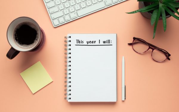 Stock photo of new year notebook with list of resolutions and objects on pink background