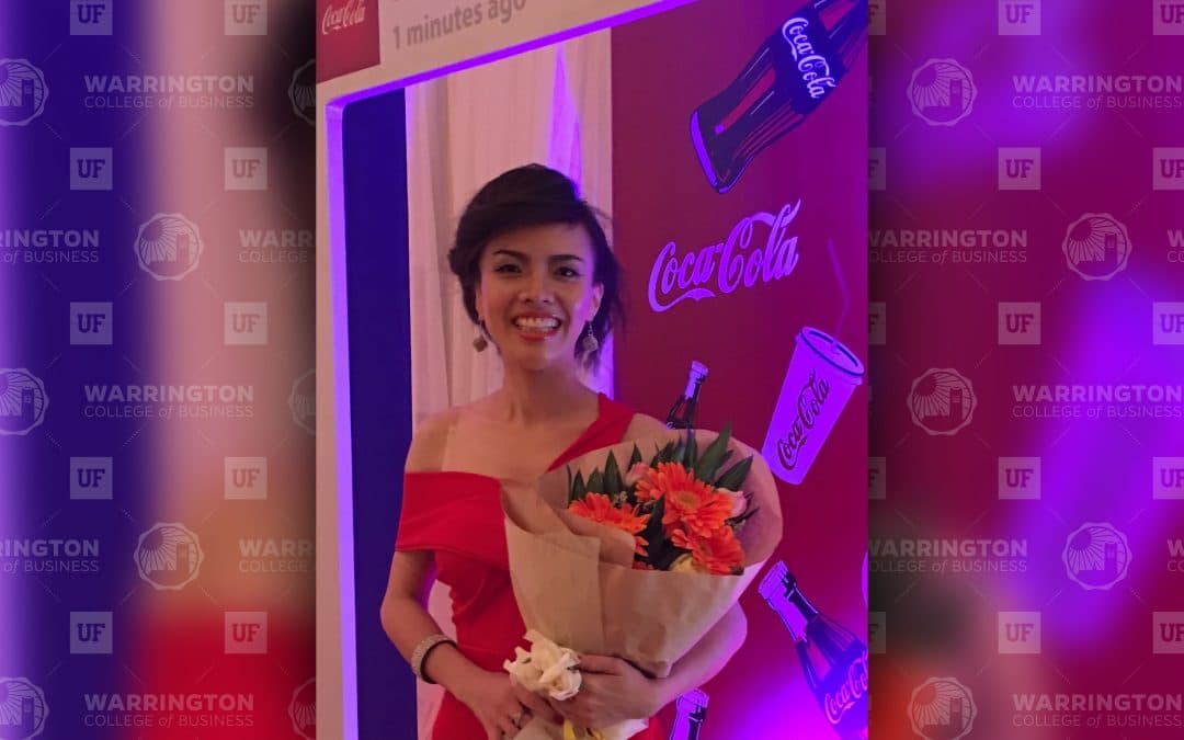 Nancy Tran holds a bouquet of flowers in front of a Coca-Cola step and repeat