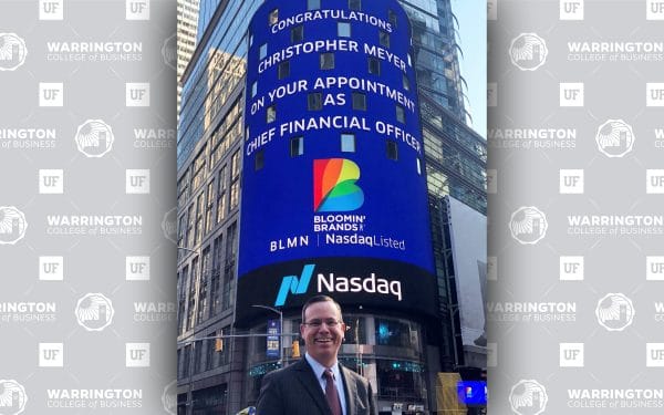Chris Meyer stands in front of a digital sign in New York City that reads 'Congratulations Christopher Meyer on your appointment as Chief Financial Officer" with the Blooming' Brands logo and NASDAQ logo.