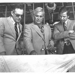 Hadley Schaefer, Robert Lanzillotti and John Simmons look down at plans for buildings on the Warrington College of Business campus.