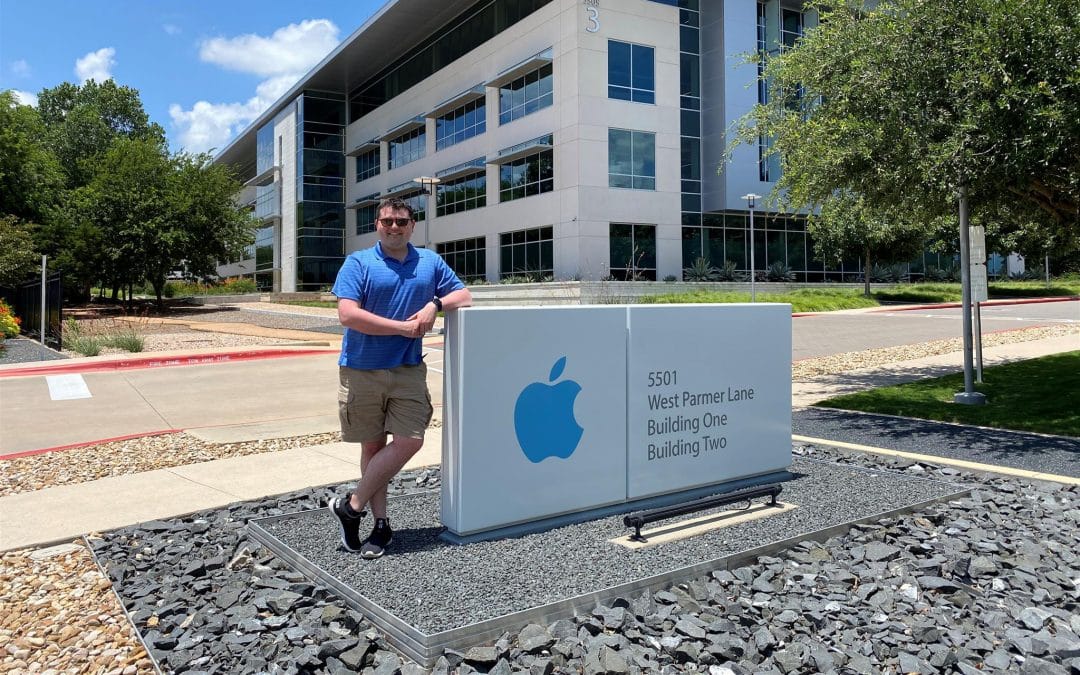 Emerson Cardoso poses for a photo by the Apple sign in front of its office building in Texas.