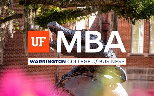 Bronze statue of an alligator on top of a globe with trees in the background and the UF MBA logo on top.