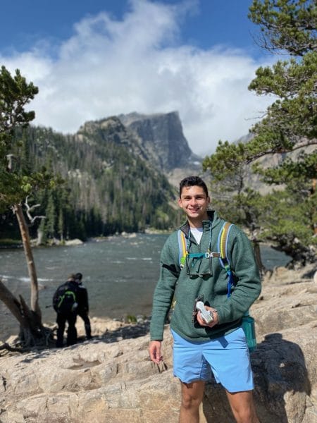 Kevin Alvarez stands in front of a mountain while hiking