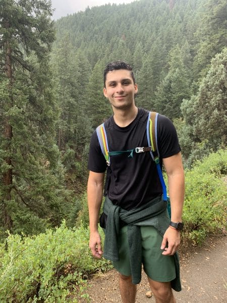 Kevin Alvarez stands on a hiking trail surrounded by trees