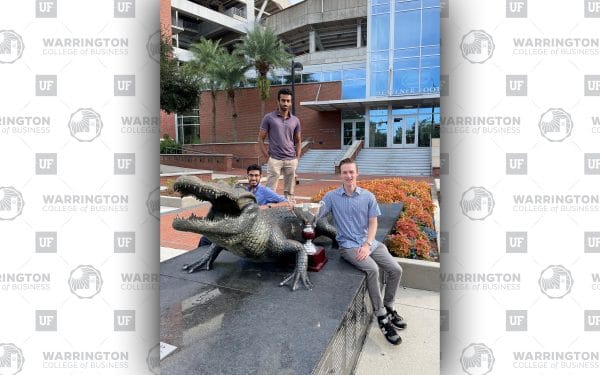 Three young men pose next to a bronze Gator statue with a trophy.