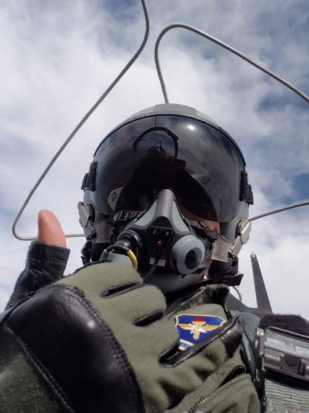 Benjamin Shu takes a selfie giving a thumbs up while flying in a military plane. 