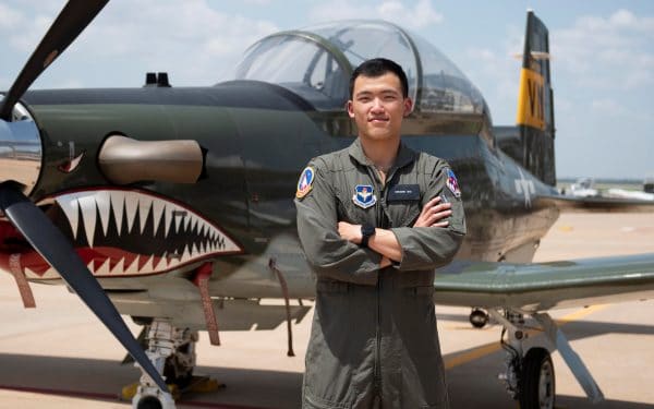 Benjamin Shu poses for a photo in his US Air Force uniform in front of a military plane.